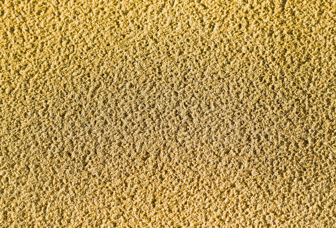 O fundo da textura da areia com uma superfície áspera do tropical