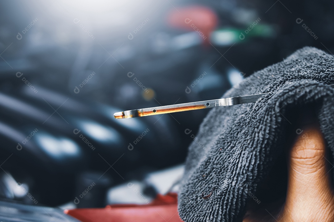 Mecânico verificando uma vareta de nível de óleo do carro do motor