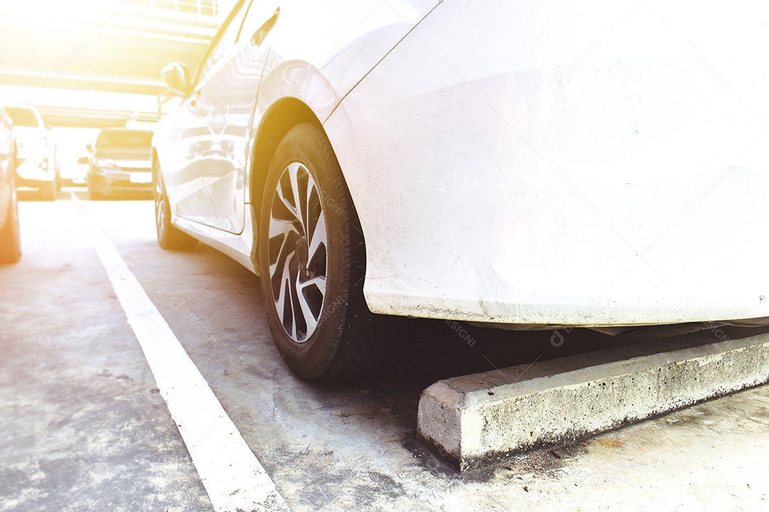 O carro branco estacionou no estacionamento com um estacionamento de cimento