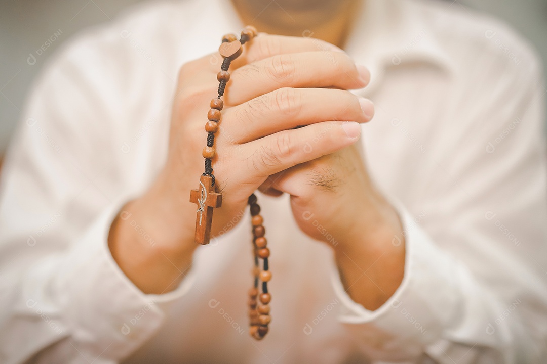 Mãos dobradas e há uma cruz em oração em uma Bíblia Sagrada