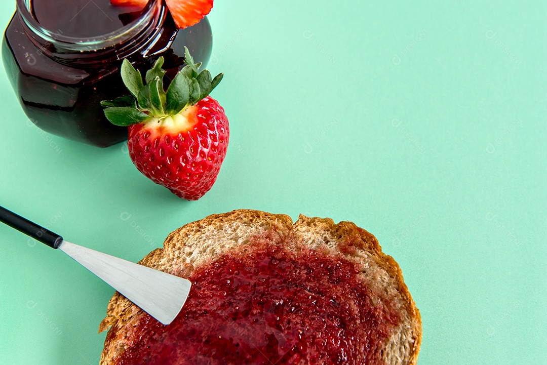 Geléia de morango e pão em um fundo verde com morangos