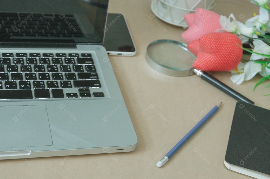 Lápis de smartphone portátil, lupa e notebook na mesa.