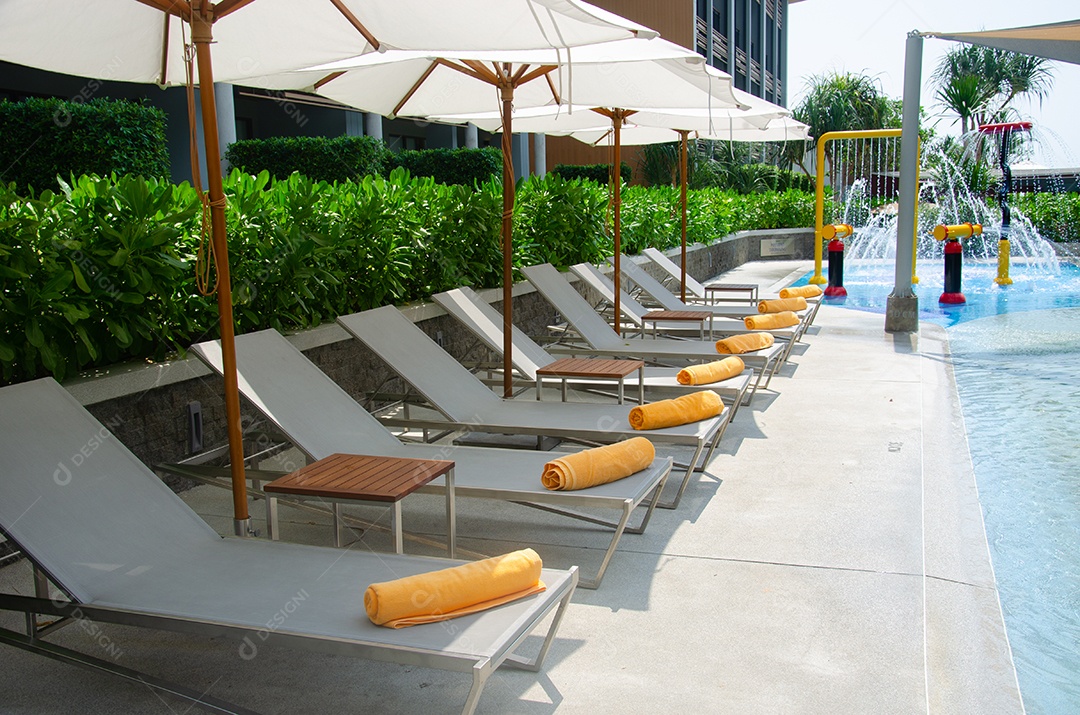 Cadeiras de luxo bonitas à beira da piscina no hotel.
