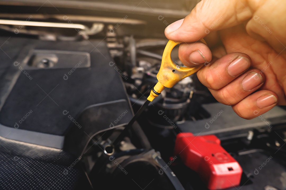 A mão do mecânico estava puxando a vareta de óleo para verificar o nível de lubrificante