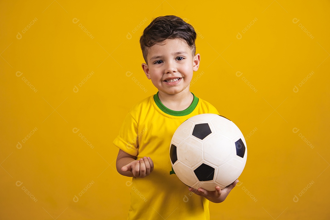 Criança vestida com camiseta do Brasil segurando uma bola de futebol