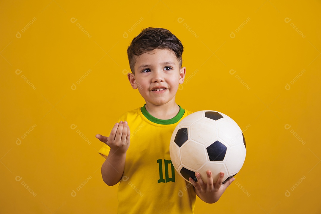 Criança vestida com camiseta do Brasil segurando uma bola de futebol