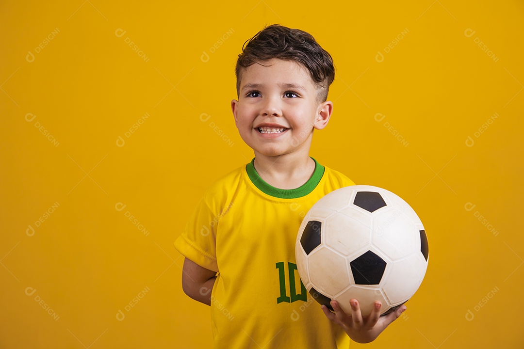 Criança vestida com camiseta do Brasil segurando uma bola de futebol