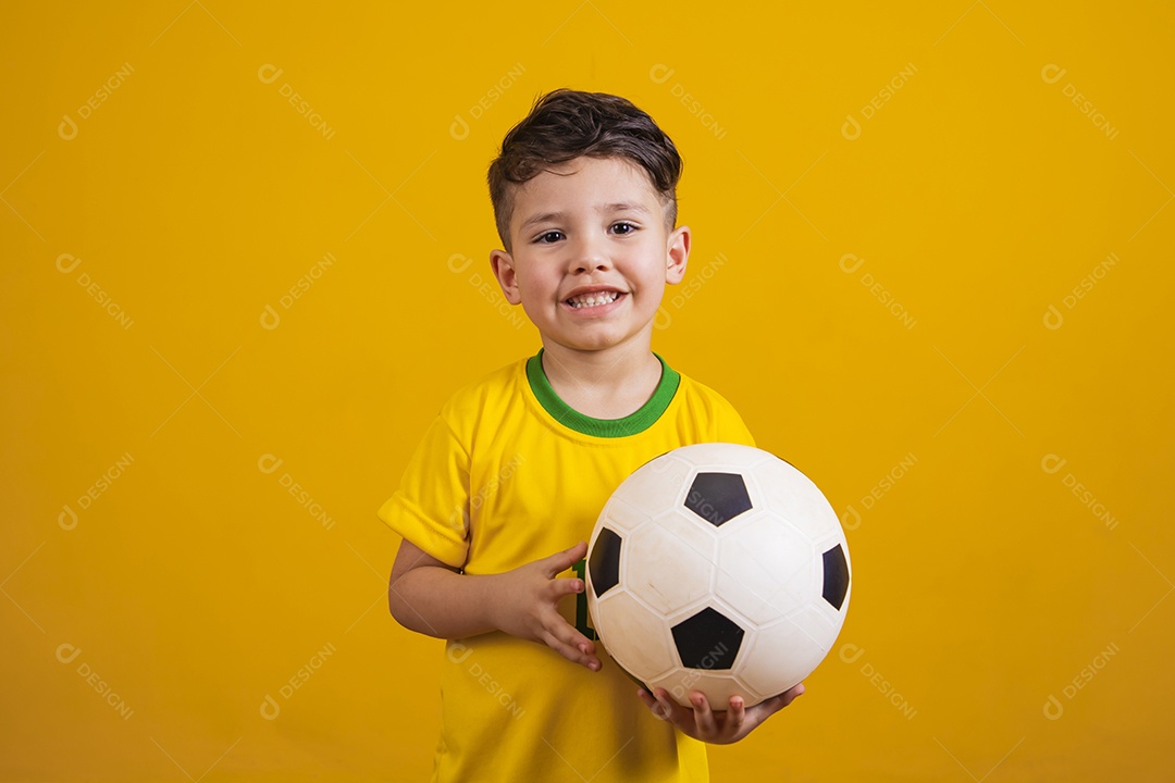 Criança vestida com camiseta do Brasil segurando uma bola de futebol