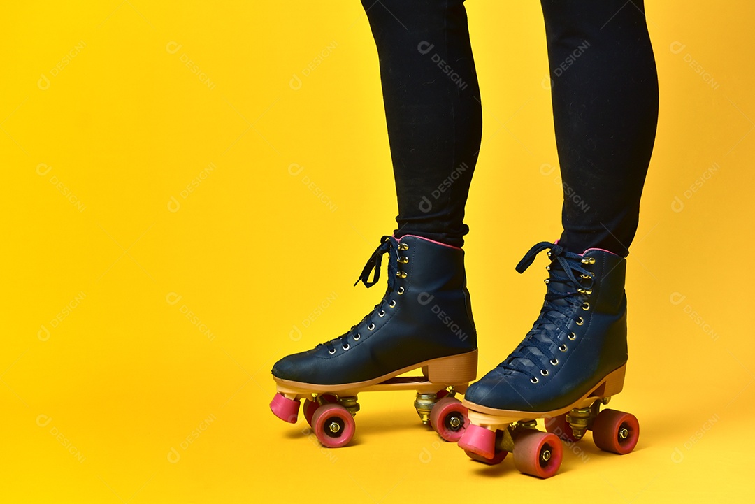 Pernas de menina usando rolo em fundo amarelo.