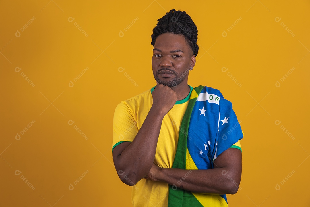 Homem brasileiro vestindo uma camiseta do Brasil segurando acessórios de torcida