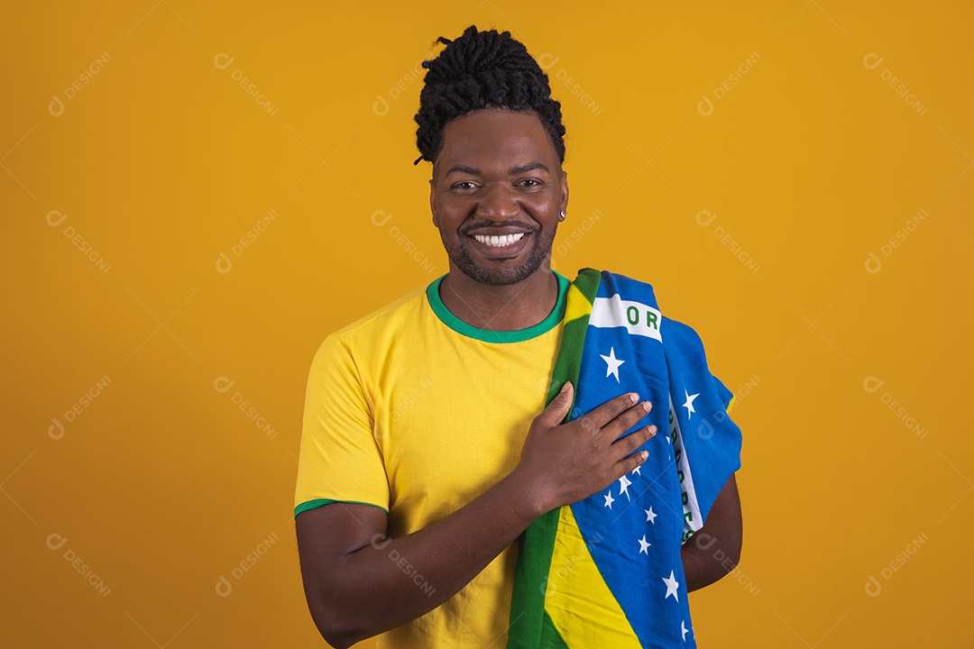 Homem brasileiro vestindo uma camiseta do Brasil segurando acessórios de torcida