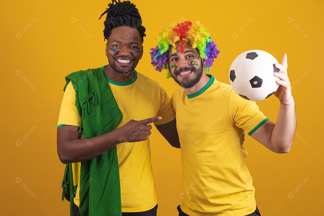 Homens brasileiros vestidos com camisetas do Brasil segurando acessórios de torcidas