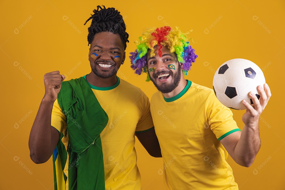 Homens brasileiros vestidos com camisetas do Brasil segurando acessórios de torcidas