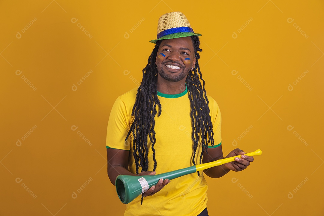 Homem brasileiro vestindo uma camiseta do Brasil segurando acessórios de torcida