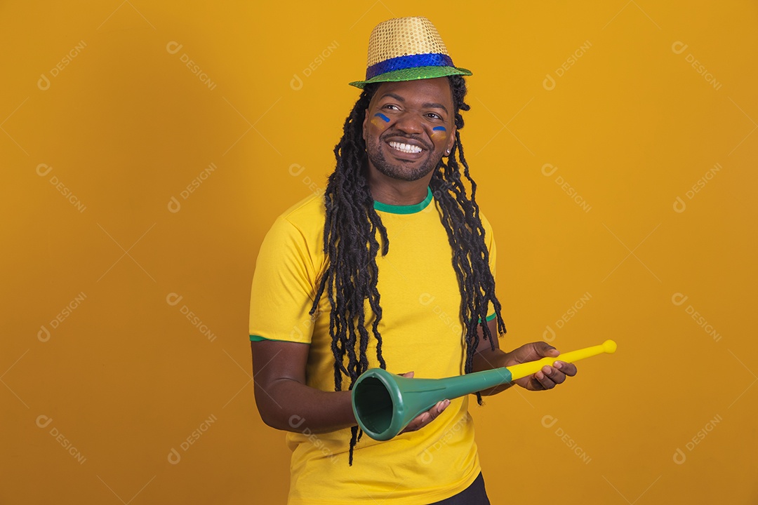 Homem brasileiro vestindo uma camiseta do Brasil segurando acessórios de torcida