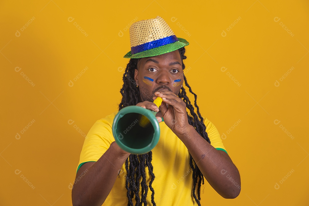 Homem brasileiro vestindo uma camiseta do Brasil segurando acessórios de torcida