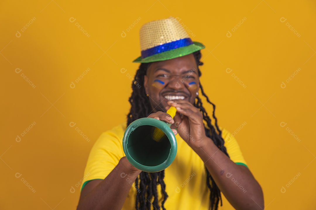 Homem brasileiro vestindo uma camiseta do Brasil segurando acessórios de torcida