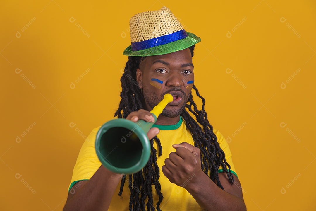 Homem brasileiro vestindo uma camiseta do Brasil segurando acessórios de torcida
