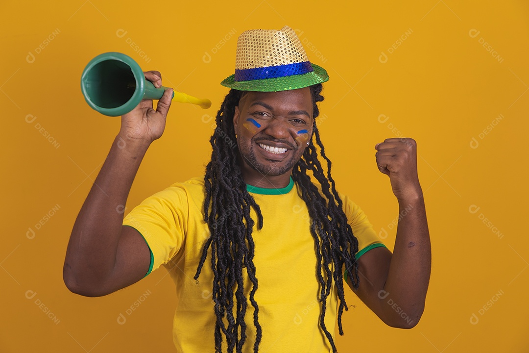 Homem brasileiro vestindo uma camiseta do Brasil segurando acessórios de torcida