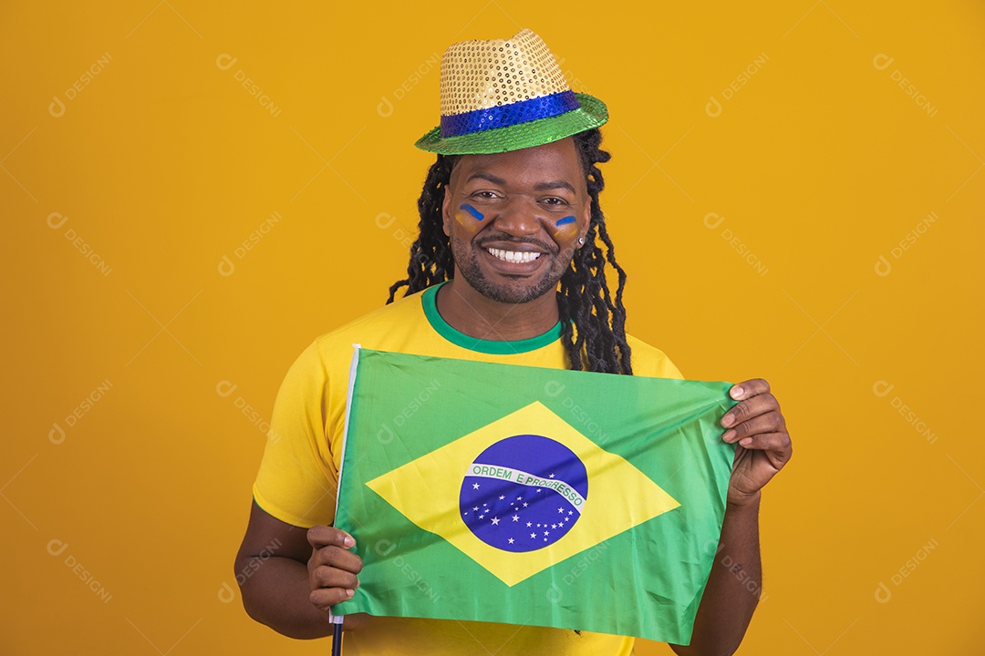 Homem brasileiro vestindo uma camiseta do Brasil segurando acessórios de torcida