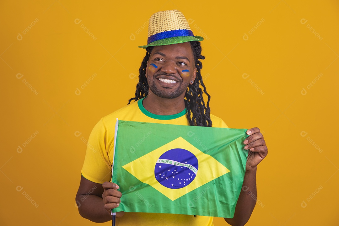 Homem brasileiro vestindo uma camiseta do Brasil segurando acessórios de torcida