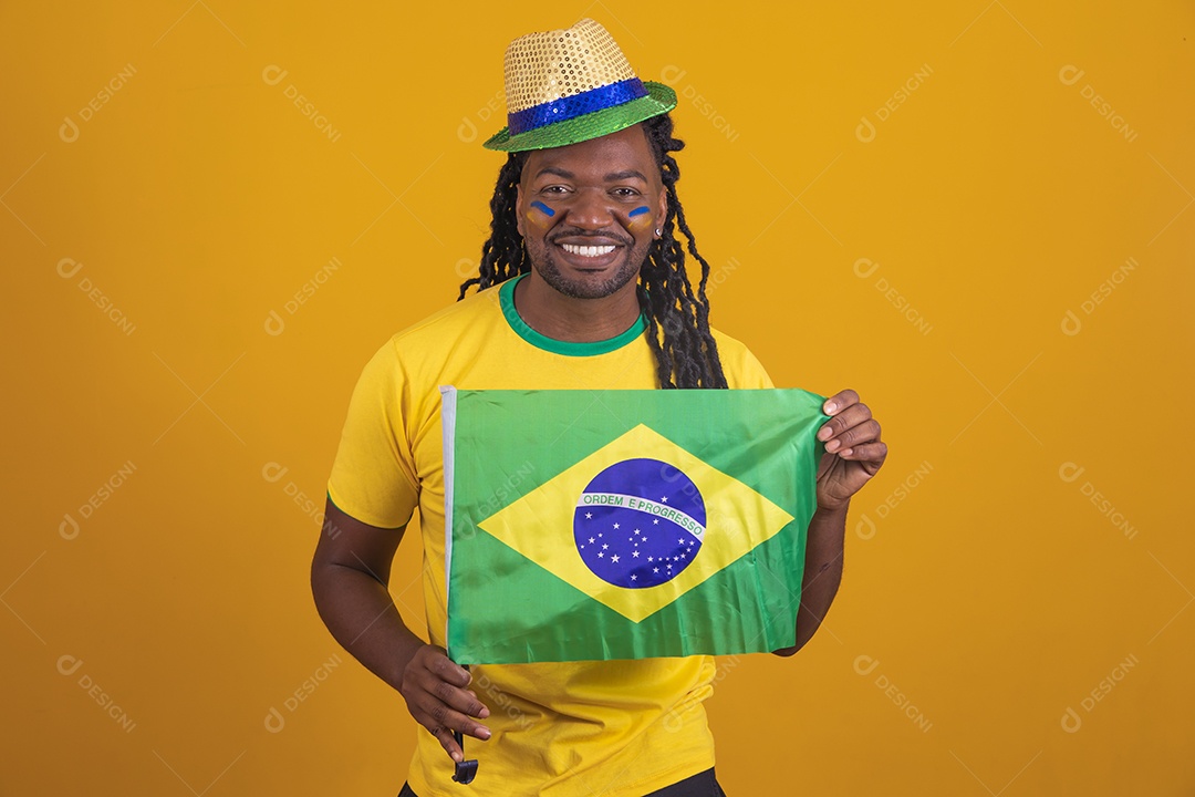 Homem brasileiro vestindo uma camiseta do Brasil segurando acessórios de torcida
