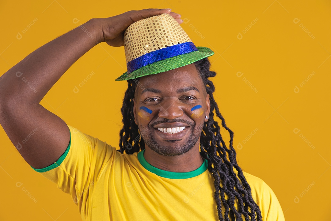 Homem brasileiro vestindo uma camiseta do Brasil segurando acessórios de torcida