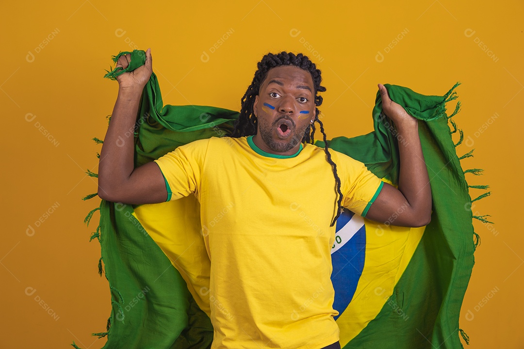 Homem brasileiro vestindo uma camiseta do Brasil e segurando a bandeira nacional