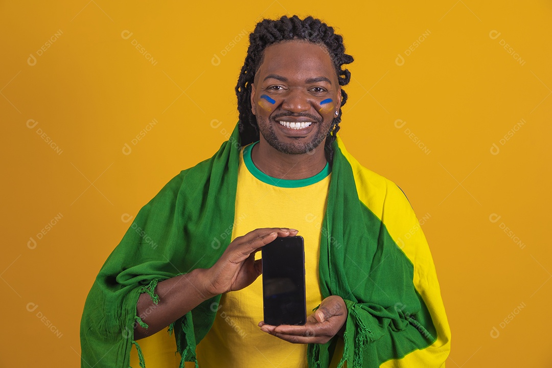 Homem brasileiro vestindo uma camiseta do Brasil e segurando um celular smartphone