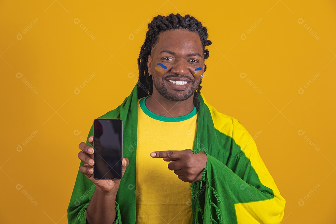 Homem brasileiro vestindo uma camiseta do Brasil e segurando um celular smartphone