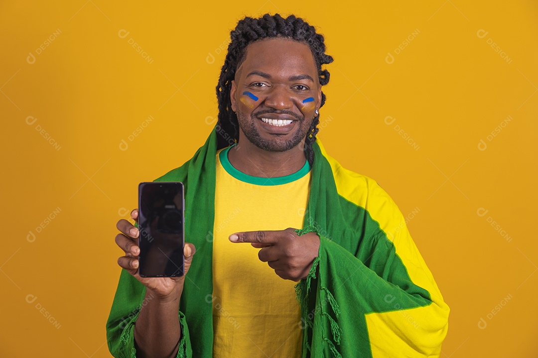 Homem brasileiro vestindo uma camiseta do Brasil e segurando um celular smartphone