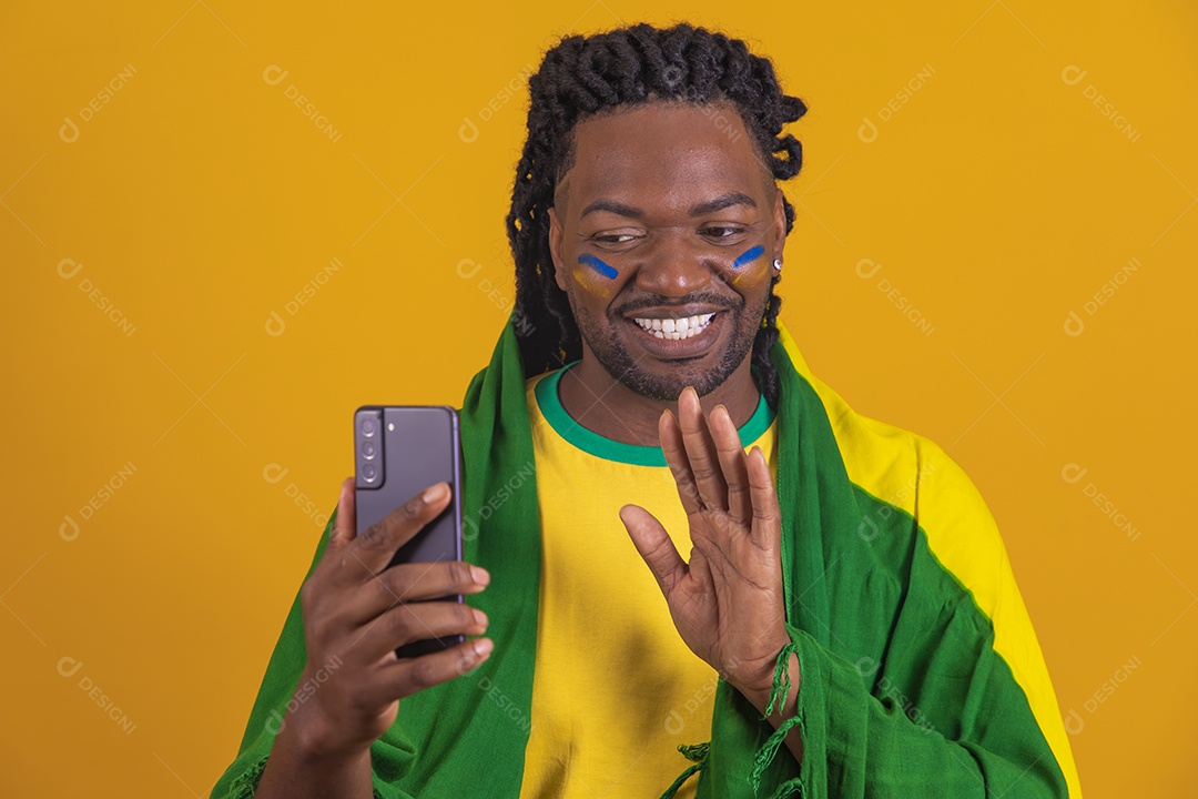 Homem brasileiro vestindo uma camiseta do Brasil e segurando um celular smartphone