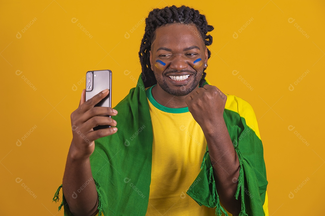 Homem brasileiro vestindo uma camiseta do Brasil e segurando um celular smartphone