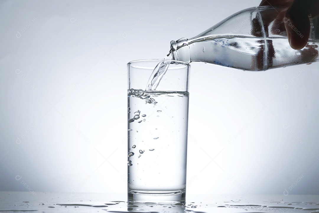 Mão segurando uma garrafa de vidro colocando água no copo.