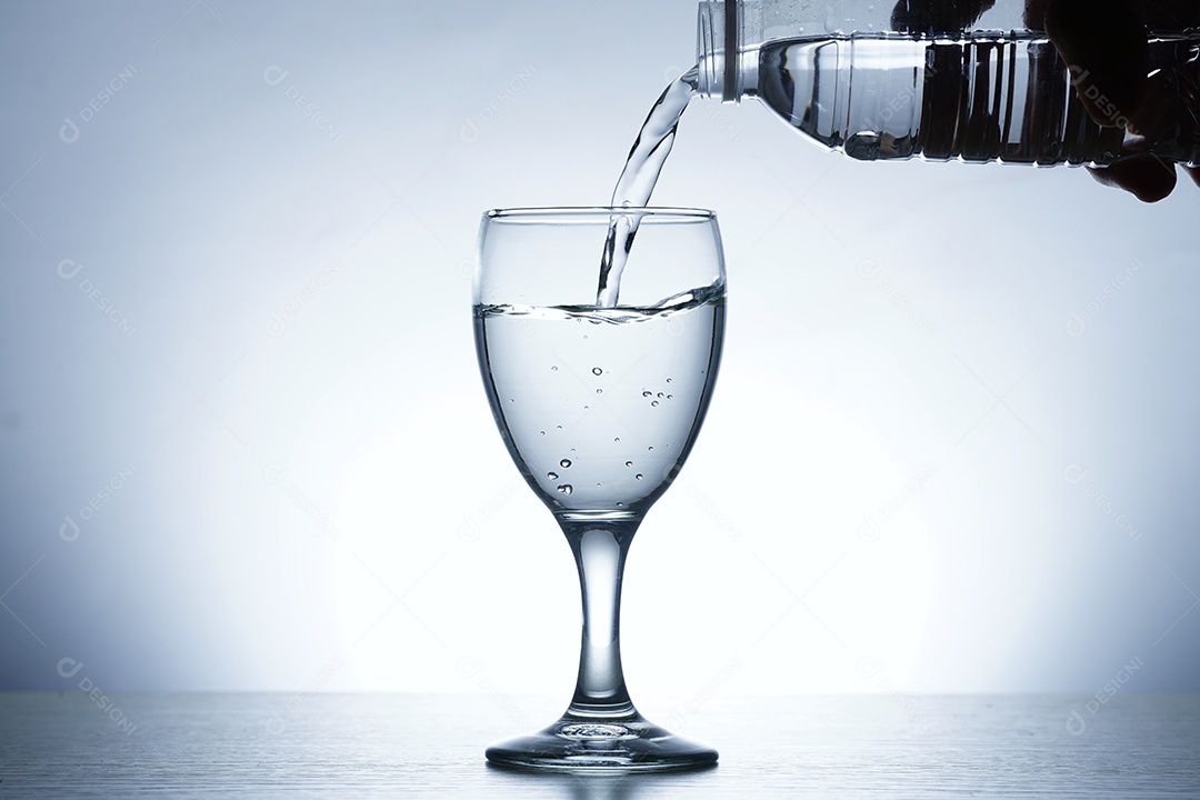 Mão segurando garrafa colocando água em uma taça.