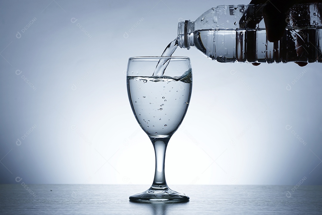 Mão segurando garrafa colocando água em uma taça.