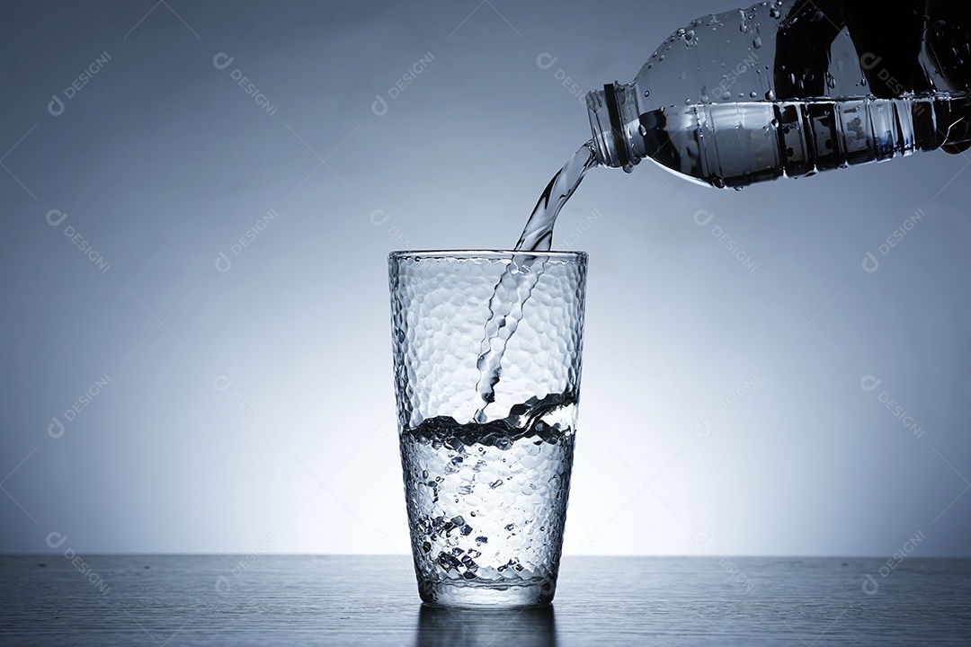 Mão com garrafa colocando água em um copo.