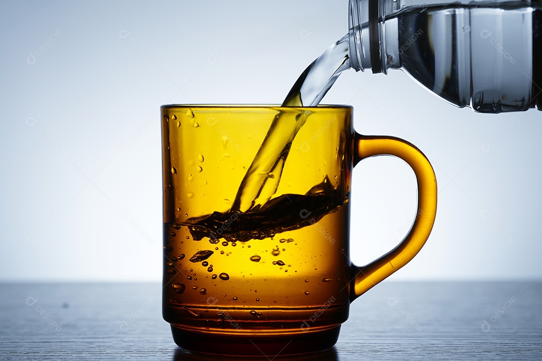 Pessoa colocando água dentro de uma xícara.