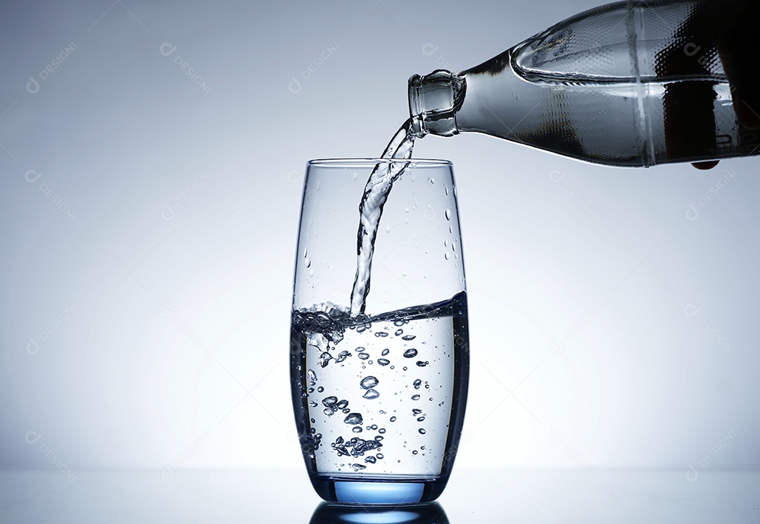 Garrafa colocando água em um copo de vidro.