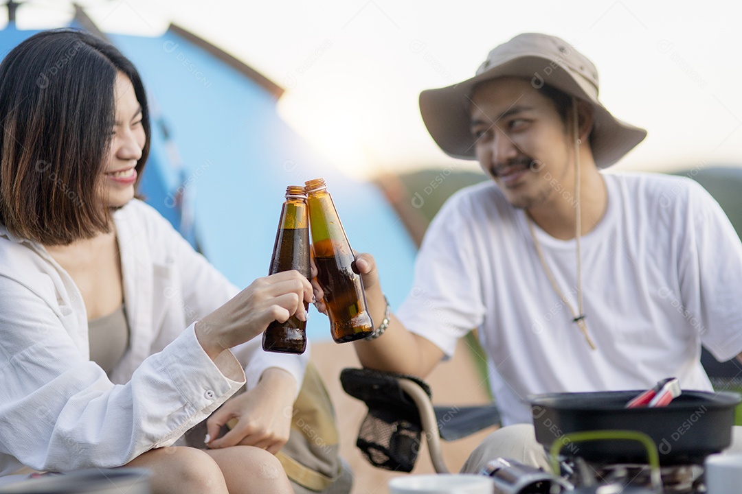 Casal asiático feliz toca guitarra e canta, gosta de acampar e beber cerveja.
