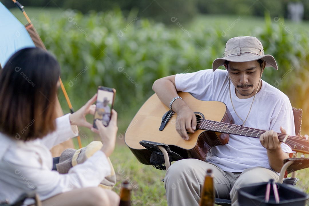 Casal asiático feliz toca guitarra e canta, gosta de acampar e beber cerveja.