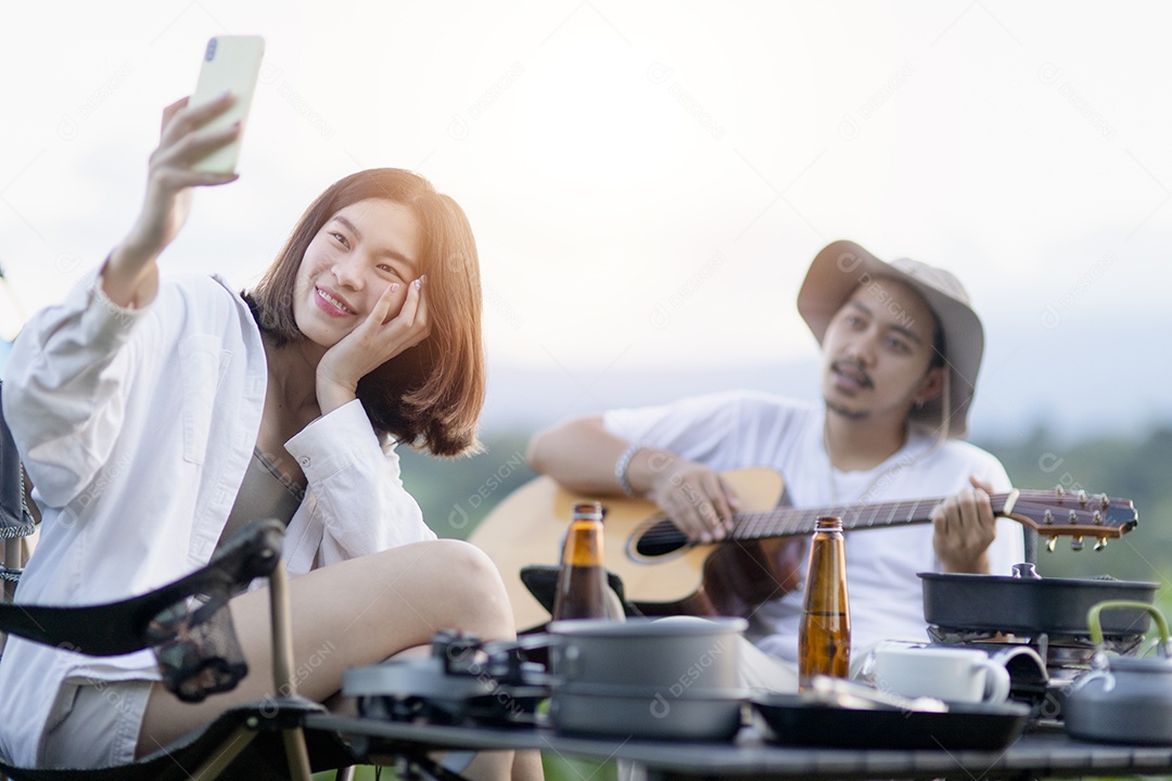 Casal asiático feliz toca guitarra e canta, gosta de acampar e beber cerveja.
