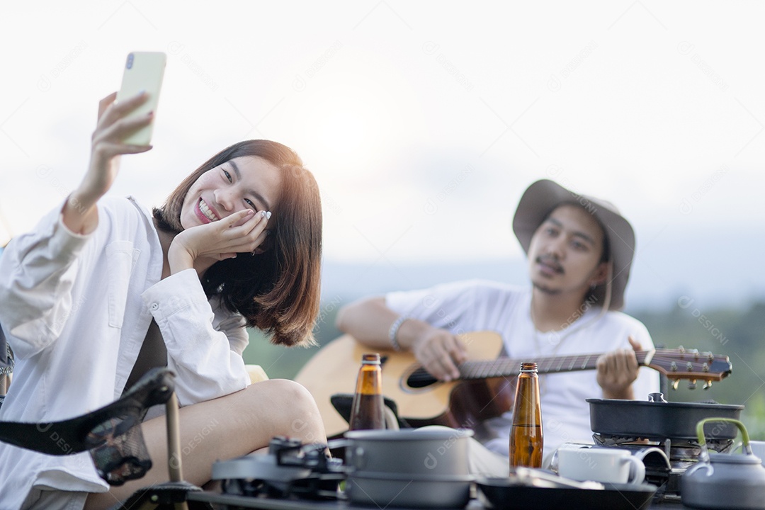 Casal asiático feliz toca guitarra e canta, gosta de acampar e beber cerveja.