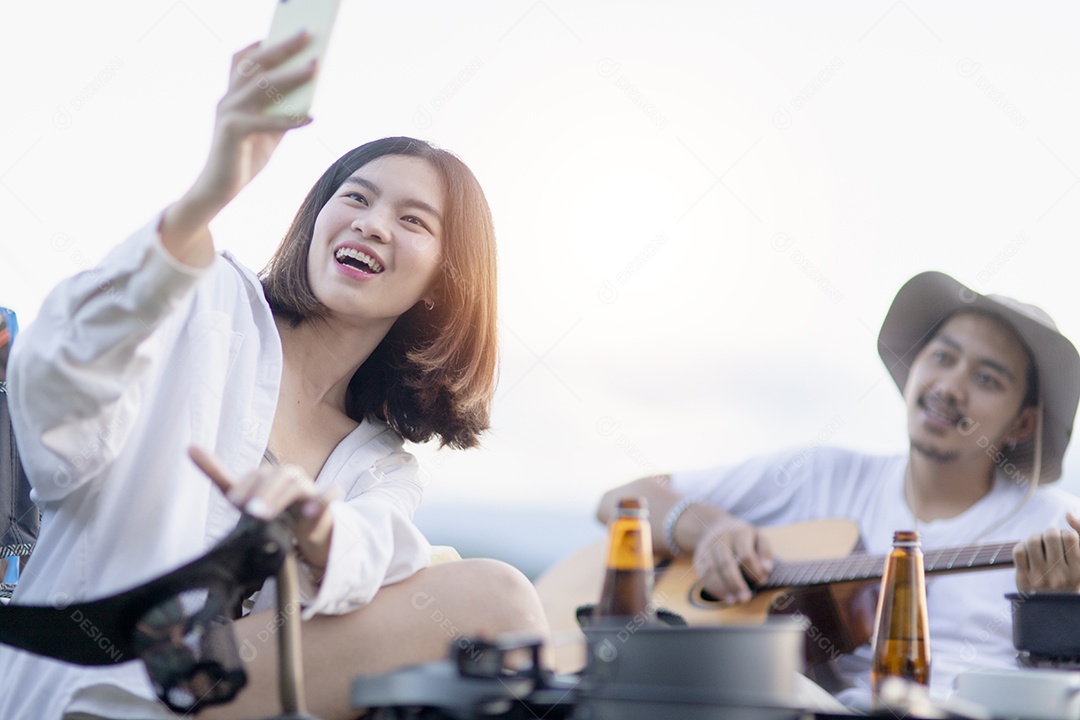 Casal asiático feliz toca guitarra e canta, gosta de acampar e beber cerveja.