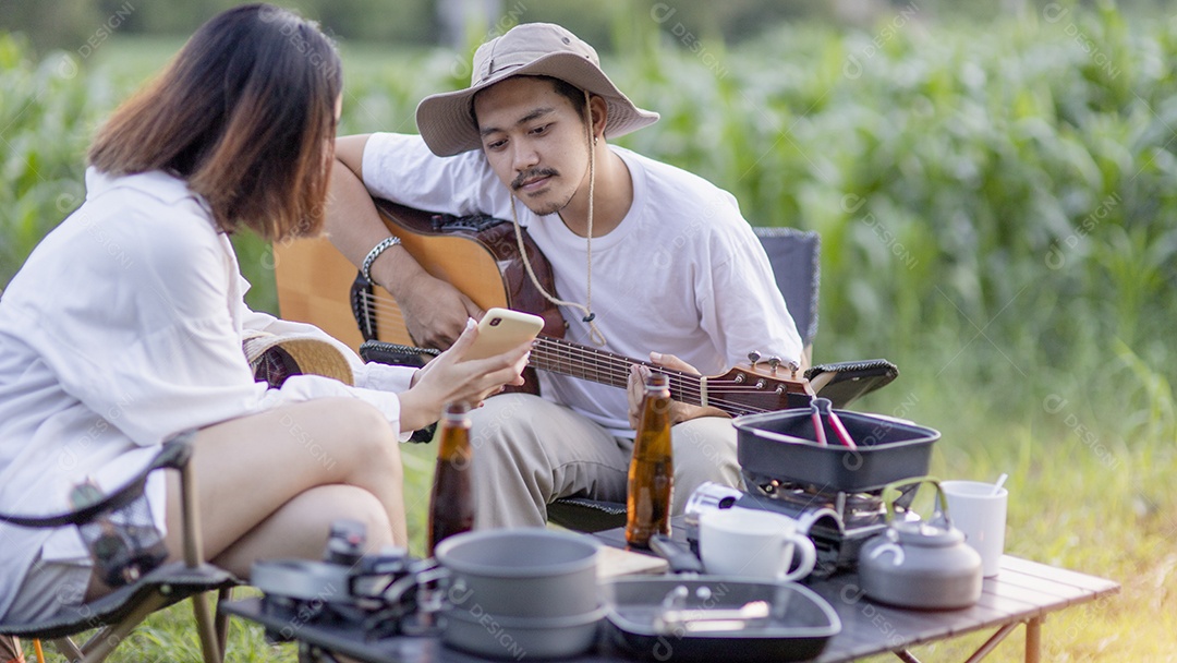 Casal asiático feliz toca guitarra e canta, gosta de acampar e beber cerveja.