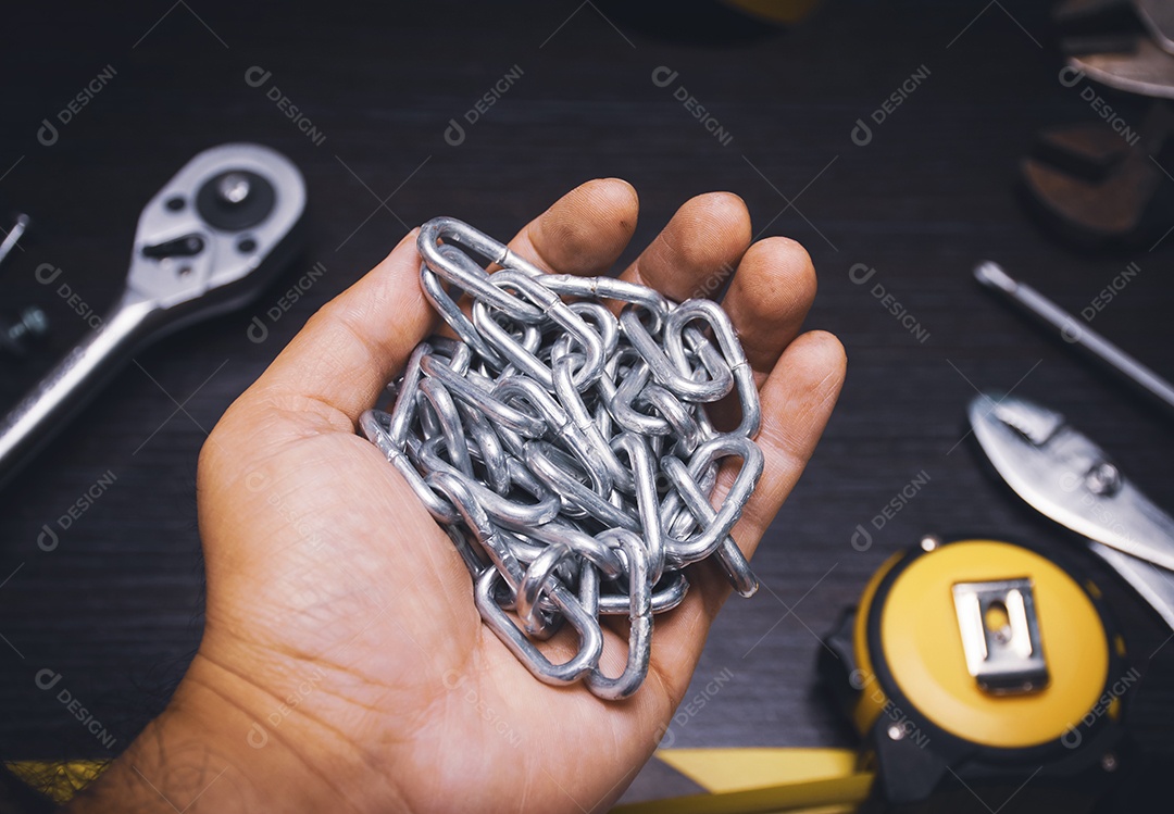 Uma corrente de metal na mão mecânica com ferramentas mecânicas em madeira
