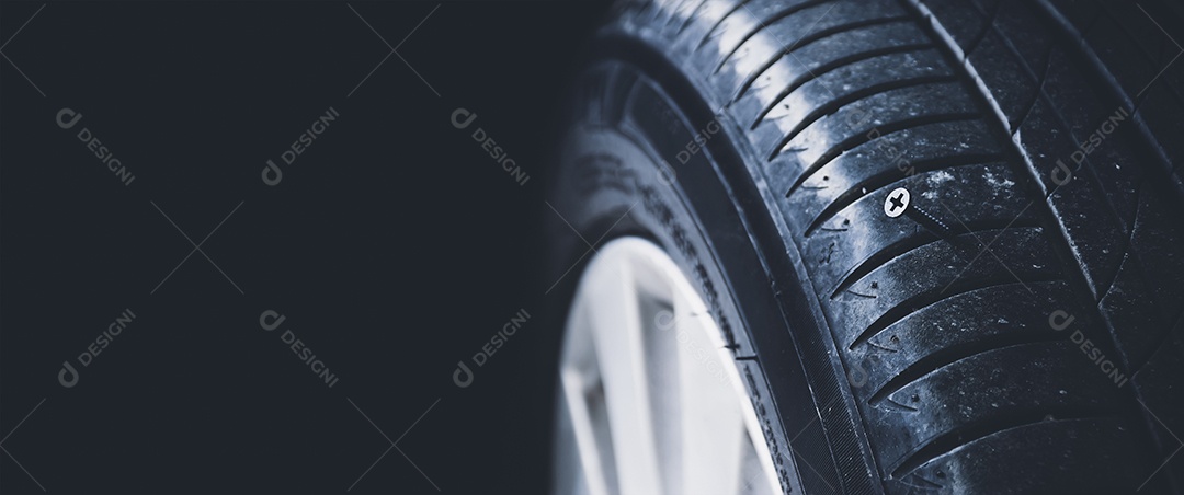 Um close-up mostra um parafuso de metal afiado perfurando um pneu de automóvel