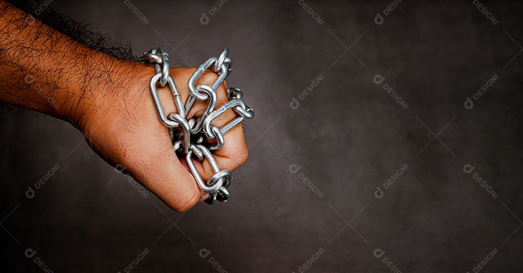 Uma corrente de metal é enrolada em um punho em um cimento escuro