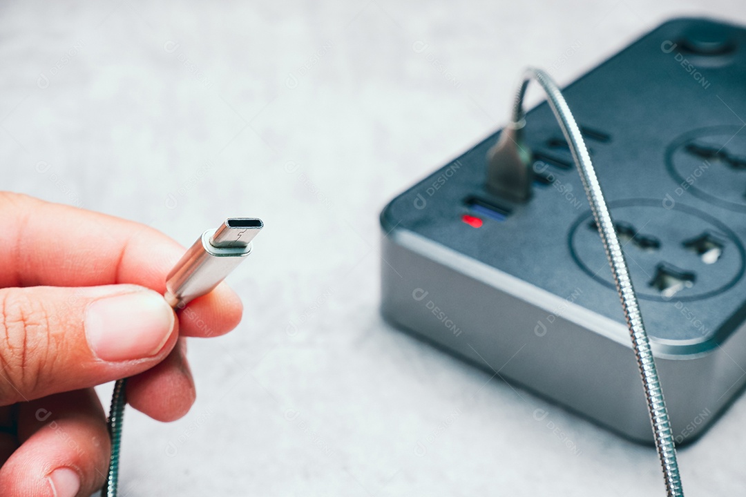 Mão humana segurando um cabo de carregador de celular tipo C conectado