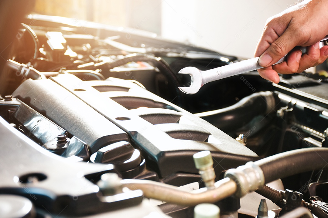 Mão do mecânico de automóveis segurando a chave de boca na comparação do motor